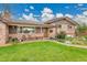 Charming brick home features a covered porch with seating and a lush, green lawn at 55 S Flower St, Lakewood, CO 80226