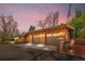 A spacious three-car garage featuring brick siding and a terraced landscape with steps leading to the yard at 5471 S Sherman St, Littleton, CO 80121