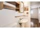 Clean bathroom featuring a pedestal sink, toilet, and wooden shelves at 3693 E Costilla Ave, Centennial, CO 80122