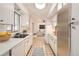 Bright galley kitchen with white cabinets, stainless steel refrigerator, and tiled floors at 3693 E Costilla Ave, Centennial, CO 80122