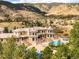 Aerial view showcasing the home's manicured grounds, inviting pool, and stunning mountain backdrop at 6729 Bear Point Trl, Golden, CO 80403