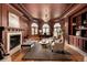 Cozy living room with a fireplace, wood paneling, comfortable seating, and arched windows at 6729 Bear Point Trl, Golden, CO 80403