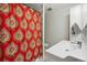 Bright bathroom featuring red patterned shower curtain, tiled backsplash, and white cabinet and sink at 8397 Chase Dr, Arvada, CO 80003