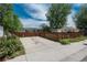 A street view of a parking area featuring a fence, greenery, and glimpses of houses in the background at 3629 W Custer Pl, Denver, CO 80219