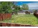 A quaint single-story home with a fenced front yard, complemented by lush green trees and sky at 3629 W Custer Pl, Denver, CO 80219
