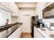 Galley kitchen features white cabinetry, black appliances, and granite countertops at 1441 N Humboldt St # 302, Denver, CO 80218