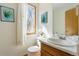 Cozy bathroom with a diamond window, decorative wall art, and neutral toned sink and toilet at 1699 S Trenton St # 147, Denver, CO 80231