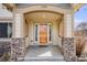 Inviting front porch with stone columns and an orange-colored front door at 1334 Carriage Dr, Longmont, CO 80501