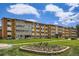 Full building exterior shot with a well-manicured lawn and vibrant flower beds under a blue sky at 9655 E Center Ave # 11D, Denver, CO 80247