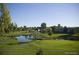 Scenic community pond with lush green landscaping and mature trees under a clear sky at 9655 E Center Ave # 11D, Denver, CO 80247