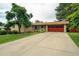 Charming brick home features a well-manicured lawn, mature trees, and a two-car garage with a red door at 1705 Lewis St, Lakewood, CO 80215