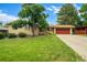 Charming brick home features a well-manicured lawn, mature trees, and a two-car garage with a red door at 1705 Lewis St, Lakewood, CO 80215