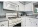 Cozy kitchen featuring white cabinets, gas range, microwave, and gray countertops at 1705 Lewis St, Lakewood, CO 80215