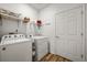 Efficient laundry room with washer, dryer, shelving, and wood-look vinyl flooring at 6912 Poudre St, Frederick, CO 80530