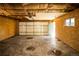 Unfinished garage with exposed insulation, wood paneling and an open garage door at 863 S Dudley St, Lakewood, CO 80226