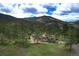 A wide aerial view of a charming residence nestled in a forest with mountain views and lush green surroundings at 207 County Road 65, Evergreen, CO 80439