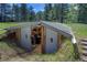 Exterior of a unique underground structure, possibly a storm cellar or greenhouse, set in a lush green field at 207 County Road 65, Evergreen, CO 80439