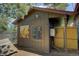 Side exterior view of an outbuilding with wooden siding, a dog kennel, and outdoor art at 207 County Road 65, Evergreen, CO 80439