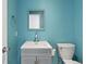 Aqua half bath features a modern vanity, mirror and toilet at 9451 W Hialeah Pl, Littleton, CO 80123