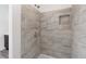 Shower featuring gray tiles, modern fixtures, and a convenient built-in shelf at 9451 W Hialeah Pl, Littleton, CO 80123