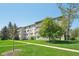 Spacious lawn and sidewalk leading to the well-maintained building under a blue sky with mature trees at 705 S Alton Way # 4D, Denver, CO 80247