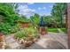 Landscaped backyard with mature trees, stone patio, an outdoor dining set, and flower beds at 3044 W 40Th Ave, Denver, CO 80211