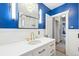 Modern bathroom with blue walls, subway tile shower, and white vanity with gold hardware and custom fixtures at 3044 W 40Th Ave, Denver, CO 80211