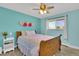 Cozy bedroom with light blue walls, wood trim, a ceiling fan, and a lovely view from the window at 16816 E Costilla Ave, Foxfield, CO 80016