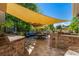 Outdoor patio with a dining area under a sun sail, BBQ, and lush landscaping at 902 Jarvis Dr, Erie, CO 80516