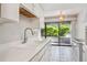 Kitchen featuring white cabinets, stainless steel faucet, and sliding glass door to patio at 6490 S Dayton St # L02, Englewood, CO 80111