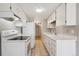 Galley kitchen featuring white appliances, tile flooring, and ample cabinet space at 6490 S Dayton St # L02, Englewood, CO 80111