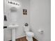 Bright half bathroom with pedestal sink, white toilet, and light wood-look vinyl floors at 857 Gold Hill Dr, Erie, CO 80516
