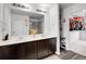 Spacious bathroom with dual sinks, large mirror, white countertops, dark wood cabinets and a walk-in closet at 857 Gold Hill Dr, Erie, CO 80516