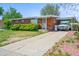 Single-story brick home featuring a covered parking area and a spacious cracked driveway at 245 S 13Th Ave, Brighton, CO 80601