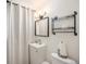 Well-lit bathroom featuring a vanity, mirror, shelving unit, and shower with a bright white curtain at 12289 W Atlantic Ave, Lakewood, CO 80228