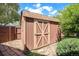 Exterior view of backyard shed featuring a wooden door, shingled roof, and adjacent landscaping at 12289 W Atlantic Ave, Lakewood, CO 80228