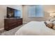 Modern bedroom featuring a large TV on a wooden dresser and a cozy white textured comforter at 13460 Broad Wing Ave, Parker, CO 80134