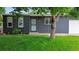 Close-up of the house's gray brick facade with a green lawn, trees, and dark trim around the windows and door at 5170 Deephaven Ct, Denver, CO 80239