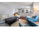 Bright living room with a sofa, blue chairs, a dark wood coffee table, hardwood floors, and an open kitchen concept at 5170 Deephaven Ct, Denver, CO 80239