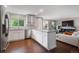 Open-concept kitchen and living area showcasing white cabinets, stainless steel appliances, wood floors, and comfortable seating at 5170 Deephaven Ct, Denver, CO 80239
