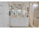 Bright bathroom featuring double vanity, large mirror with lighting, and tiled shower with built in shelving at 10540 Tracewood Cir, Highlands Ranch, CO 80130