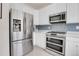 Modern kitchen with stainless steel appliances, white cabinetry, and tiled backsplash at 10540 Tracewood Cir, Highlands Ranch, CO 80130