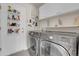 Efficient laundry room features LG washer and dryer, white cabinets, shelving and door storage for cleaning supplies at 10540 Tracewood Cir, Highlands Ranch, CO 80130