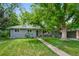 Charming home with a well-manicured lawn and mature trees, complemented by a welcoming walkway at 6283 S Prescott St, Littleton, CO 80120