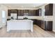 Modern kitchen with stainless steel appliances, island, and dark cabinets at 683 N Deer Park St, Watkins, CO 80137