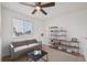 Cozy bedroom setup with a comfortable gray couch, bookshelves, ceiling fan, and natural light from a window at 1623 E 164Th Pl, Brighton, CO 80602