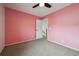 Pink bedroom features a ceiling fan, neutral carpet, and leads to hallway and stairway at 1623 E 164Th Pl, Brighton, CO 80602