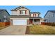 Two-story home with gray siding, brick accents, a white garage door and red window trim at 1623 E 164Th Pl, Brighton, CO 80602