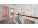 Light-filled hallway with wood and white railing, featuring neutral carpet and access to multiple rooms at 1623 E 164Th Pl, Brighton, CO 80602