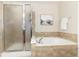 Modern bathroom features a separate shower and tub with tan tiled walls at 22725 E Ottawa Pl, Aurora, CO 80016